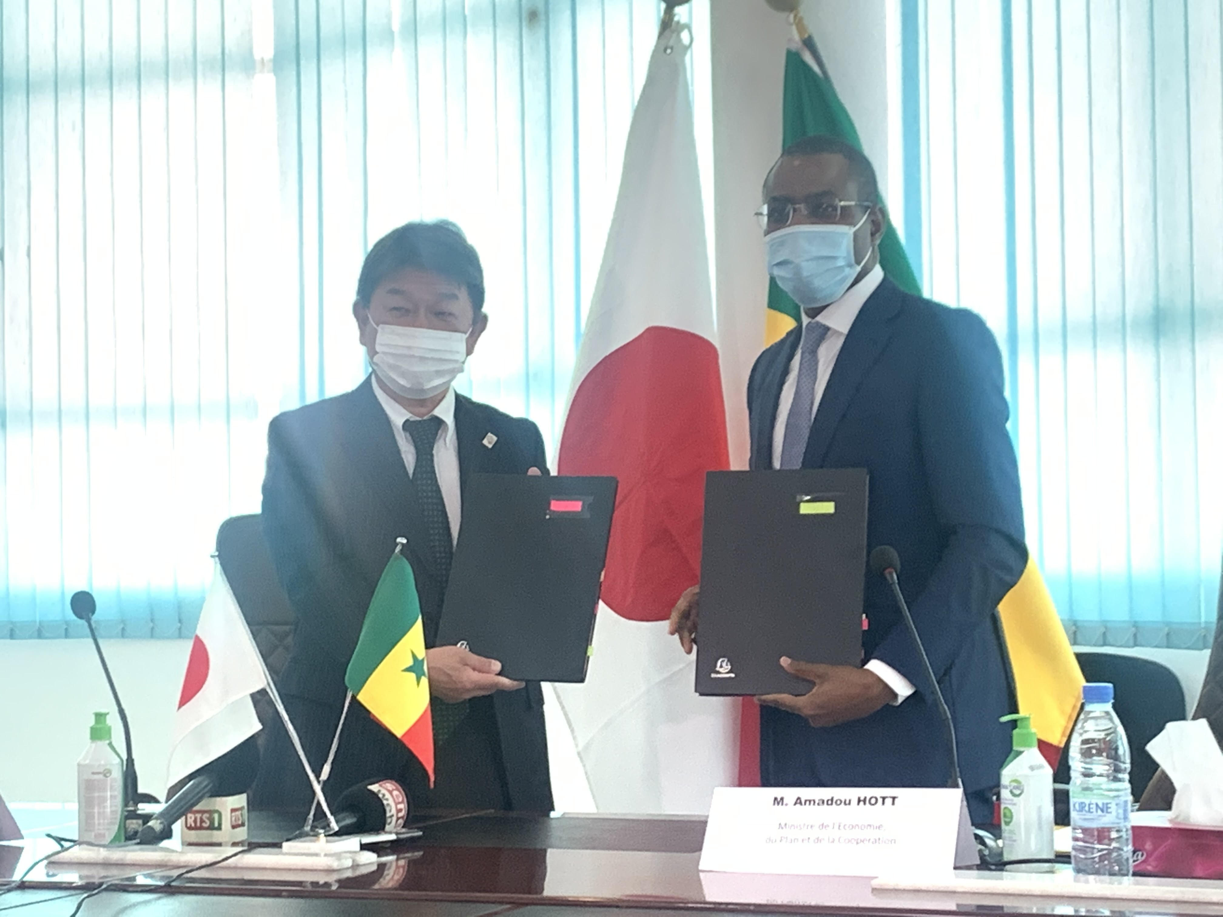 Echange de notes relatif au Projet de production de riz irrigué dans la vallée du fleuve Sénégal entre Amadou Hott, ministre sénégalais de l’Economie, du Plan et de la Coopération, et Motego Toshimitsu, ministre des Affaires étrangères du Japon.